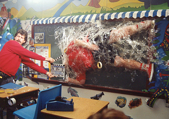 Photo of Eric Edwards about to get taped up on chalkboard